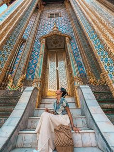 a woman sitting on some steps in front of a building with blue and gold tiles