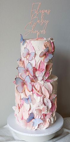 a three tiered cake with pink and blue butterflies on it's top layer