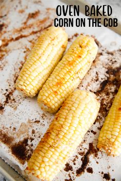 three ears of corn on a baking sheet