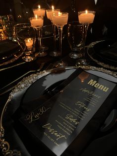 a menu on a black plate with gold trimmings and candles in the background