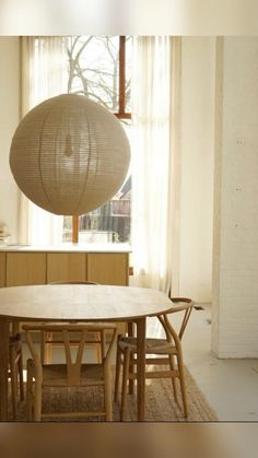 a table and chairs in front of a window with a large light fixture hanging from the ceiling