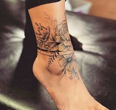 a woman's foot with flowers on it and a tattoo design on the ankle