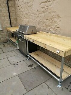 an outdoor bbq with two grills and shelves on the side of a building