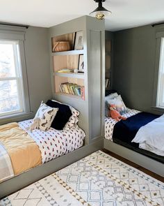 two twin beds in a bedroom with bookshelves on the wall and a rug on the floor