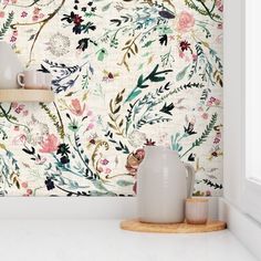 a white vase sitting on top of a counter next to a wallpapered wall