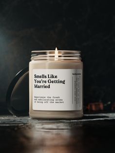 a candle sitting on top of a table next to a black mug with the words smile like you're getting married