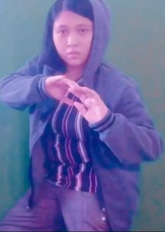 a young woman in a hoodie is posing for the camera with her hands together