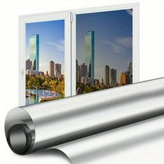 an open window showing the view of a city and river from inside it, with a roll of silver foil in front