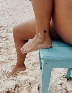 a woman's bare legs on a blue bench at the beach