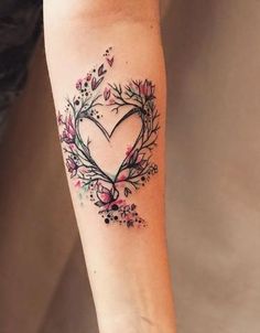 a woman's arm with a heart shaped tattoo on the left side of her arm