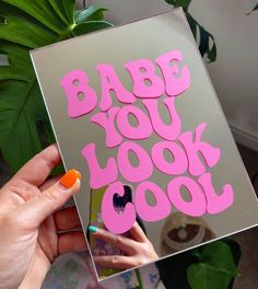 a person holding up a card with the words babe you look cool on it in pink