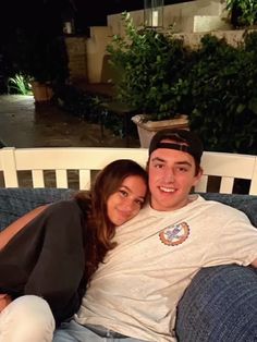 a man and woman sitting on top of a couch next to each other at night