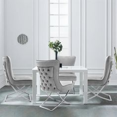 a white dining table with chairs around it and a potted plant in the corner