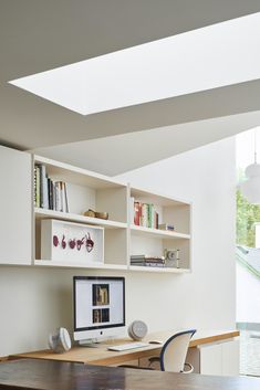 a desk with a computer on top of it in front of a book shelf filled with books