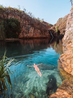 a person swimming in the water near some rocks