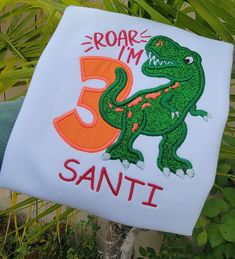 someone holding up a t - shirt that says roar i'm 3 santi