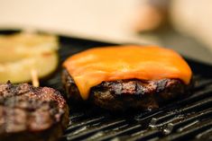 hamburgers and pickles are cooking on the grill