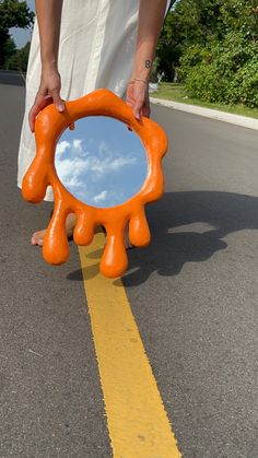 a person is holding an orange mirror on the road