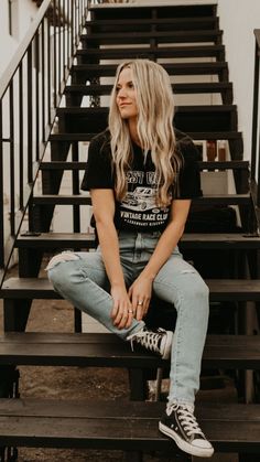 a woman sitting on some stairs with her legs crossed