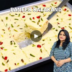 a woman standing in front of a pan filled with rice and toppings on it