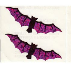 two purple bats on white paper with black and pink glitters in the shape of bat wings