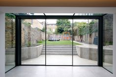 an empty room with glass doors leading to the back yard, and a playground in the background