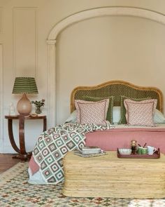 a bed with pink and green pillows in a bedroom next to two lamps on either side of the bed