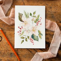 a card with flowers on it next to a pencil and some fabric, along with a pair of scissors