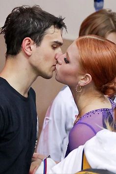 a man and woman kissing each other in front of people