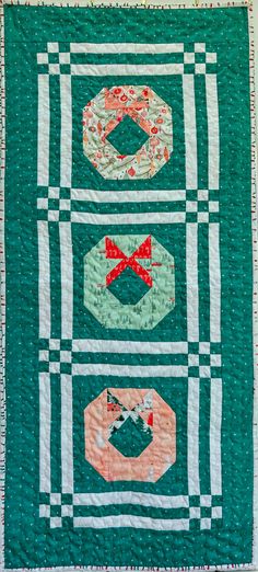 a green quilted wall hanging with three different designs on the front and back of it