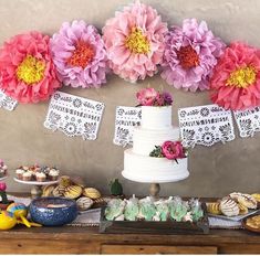 a table topped with cakes and desserts covered in paper flowers