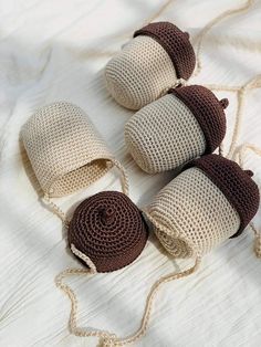 four crocheted objects are laying on a white sheet and one is brown, the other is beige