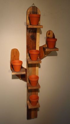 a wooden shelf with pots and pans on it, hanging from the wall in front of a white wall