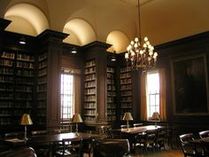 an empty library with tables and chairs in front of two large bookshelves filled with books