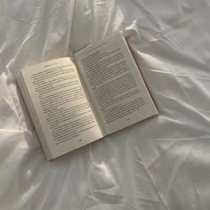 an open book laying on top of a white sheet