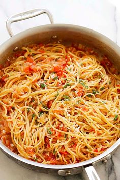 a pan filled with pasta and sauce on top of a marble counter