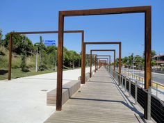 a long wooden walkway with metal posts on both sides and an empty street in the background