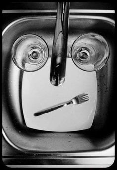 two wine glasses sitting on top of a sink with a fork and knife in it