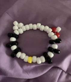 two bracelets made out of candy and black, white, and yellow beads on a purple cloth