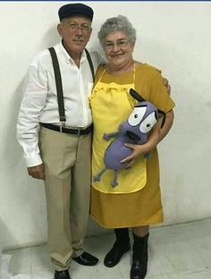 an older man and woman standing next to each other in front of a white wall