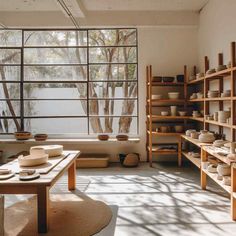 a room filled with lots of shelves and bowls on top of wooden shelves next to a window