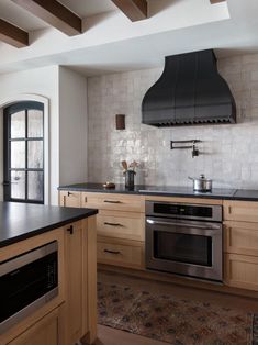 a kitchen with wooden cabinets and black counter tops, an oven hood over the stove