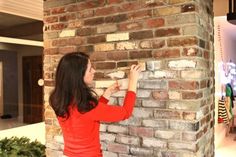 a woman is placing bricks on a brick wall