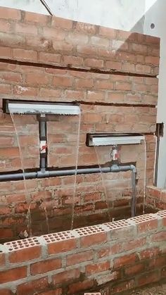 an unfinished brick wall with pipes running from it to the floor and in between them