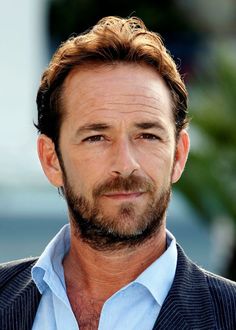 a close up of a person wearing a suit and tie with a goatee beard