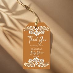 an orange tag that says thank you with white flowers and leaves on it, hanging from a string