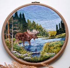 a moose is standing in the water by some trees and grass, painted on a wooden frame