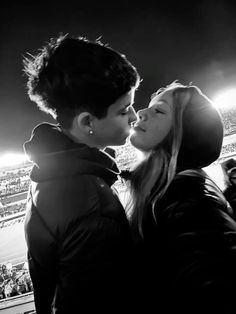 black and white photo of two people kissing in front of an audience at a sporting event