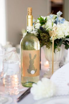 a bottle of wine sitting on top of a table next to a vase filled with flowers