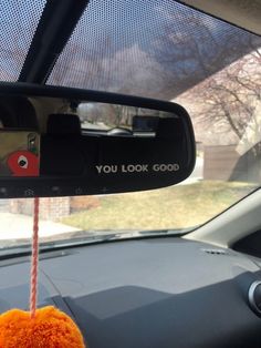 a car mirror with an orange pom - pom hanging from it's side